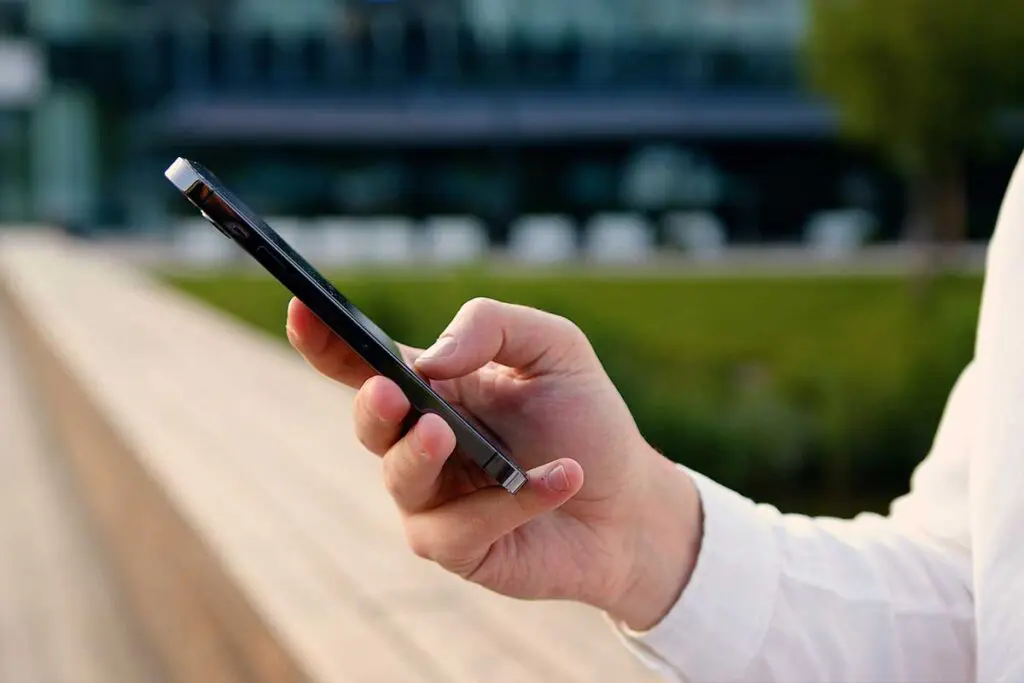 Użytkownik trzymający smartfon z dostępem do sieci 5G na zewnątrz